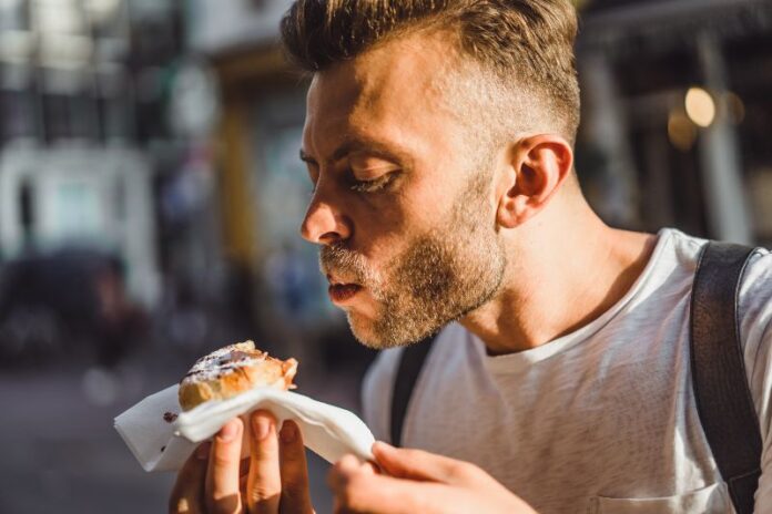 man eating dutch waffles in the street near cafe. Street food in Holland.